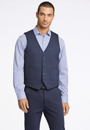 Gilet bleu marine avec deux poches avant, cinq boutons et une coupe ajustée, associé à une chemise habillée rayée bleu clair.