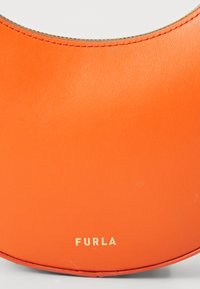 Oranje leren handtas met een gebogen ontwerp; bevat gouden hardware en een gegraveerde "FURLA" branding aan de onderkant. Soepele textuur.