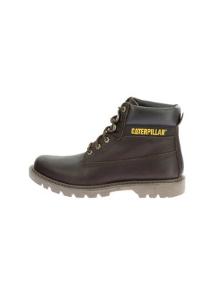 Botín de trabajo de cuero marrón con un acabado texturizado, cordones planos, suela de goma y logo amarillo de "CATERPILLAR" en el lateral. Diseño de altura hasta el tobillo.