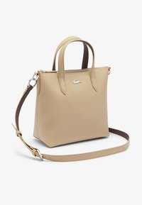 Borsa a mano in pelle beige con finitura testurizzata, doppio manico superiore, tracolla distaccabile e accento del logo argentato sulla parte anteriore.