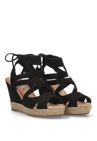 Sandalias de cuña negras con múltiples tiras entrecruzadas, diseño de punta abierta y una plataforma envuelta en yute texturizado. Material de ante suave.