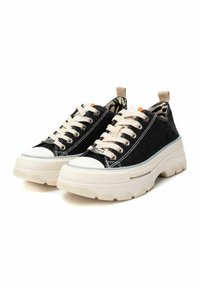 Zapatillas de lona negras con cordones crema y una parte superior texturizada. Suelas blancas gruesas con interior estampado y tirador en el talón.