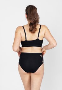 Zwarte beha en high-waisted onderbroek met kantafwerking. Zacht materiaal, verstelbare bandjes en een gladde afwerking. Geen extra accenten of patronen.