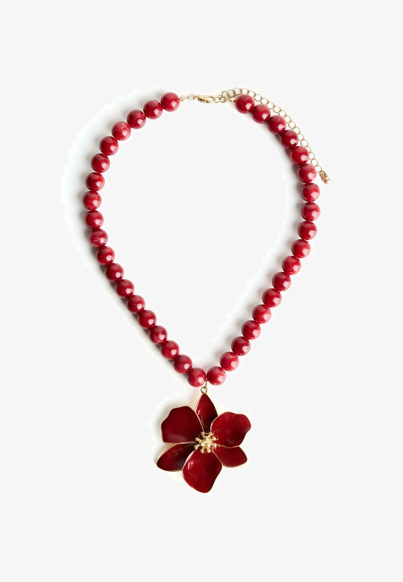 Röd pärlhalsband med blanka, sfäriska pärlor och en stor röd blommepadang med gyllene accenter och detaljerade kronblad.