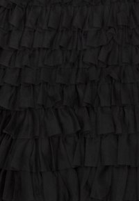 Black fabric with layered, textured ruffles. Each ruffle has a slightly irregular shape, creating a dynamic visual effect.