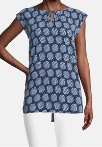 Tmavě modrý top s výstřihem ve tvaru klíče a krátkými rukávy, pokrytý světle modrými vzory listů na hladkém, jemném materiálu.