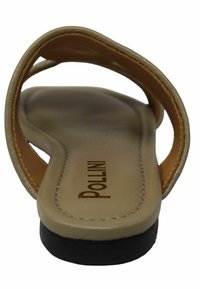 Sandalo piatto beige con design della tracolla in pelle marrone. Presenta una soletta testurizzata e una suola in gomma nera. Logo "Pollini" stampato sulla soletta.