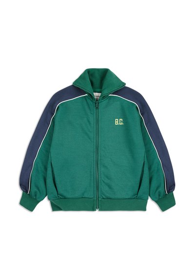 Zelená mikina so zipsom, vysokým golierom, námorníckymi modrými ramenami, bielym lemovaním a vyšitým logom "B.C." v žltom.