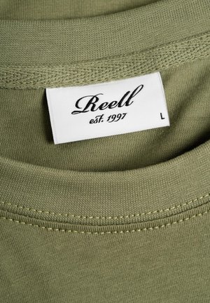 Olive green cotton t-shirt with a crew neckline. Visible label with "Reell" and "est. 1997" in black on a white background, size L.