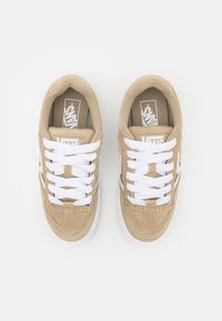 Lysbrune ruskinds sneakers med hvide snørebånd. Funktioner inkluderer logo på tungen, perforerede detaljer og en hvid gummisål. To sko vist.