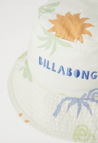Biela kyblová čiapka s kvetinovými vzormi v oranžovej a zelenej farbe, s modrým vyšívaným textom "BILLABONG" vpredu. Textúrovaná tkanina.