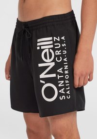 Schwarze Badeshorts mit einem Kordelzugbund, versehen mit großem weißem "O'Neill"-Logo und Text. Glatte Textur, knielanges Design.