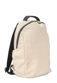 Mochila de color beige claro con una textura suave, acentos negros y un diseño sencillo. Cuenta con tirantes ajustables y un logo en la parte frontal.