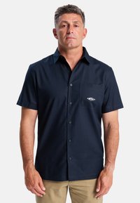 Korte mouwen, marineblauwe button-up shirt met een voorzak en geborduurd logo detail. Gemaakt van lichte, gladde stof.
