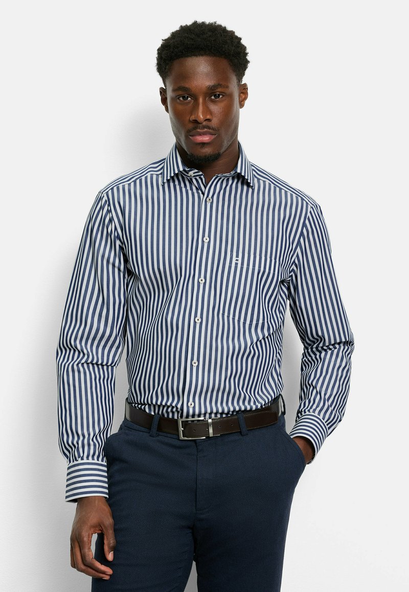 Camicia a righe blu e bianche con colletto, maniche lunghe e tasca sul petto. Indossata con pantaloni scuri e una cintura marrone.