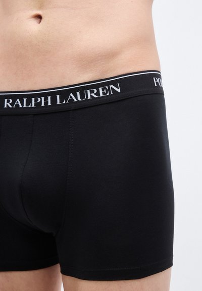 Juodos medvilninės bokserinės kelnaitės su elastine liemene, ant kurios baltos spalvos užrašas „RALPH LAUREN“. Lygios tekstūros, aptempto dizaino, iki vidurio šlaunies ilgio.