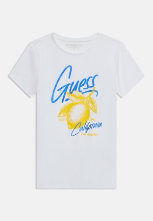 Maglietta bianca a maniche corte con scritta "Guess" blu, grafica di un limone giallo e la stampa "California Los Angeles Est. 1981" sul davanti.