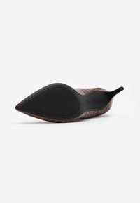 Scarpa marrone con punta a punta, dotata di un esterno testurizzato, con un design elegante e una suola in gomma nera con una presa a motivi.