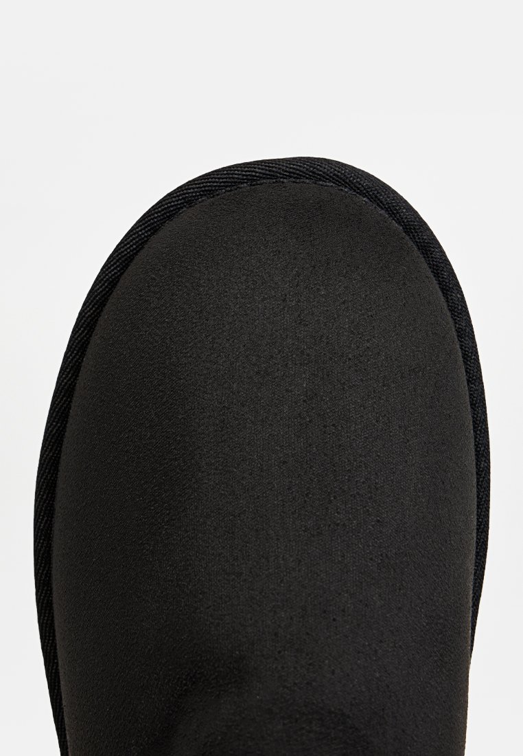 Schwarzer, strukturierten Stiefel mit runder Zehenform und glattem Obermaterial, ausgestattet mit einer gesteppten Kante entlang des Rands. Schlichtes Design, keine sichtbaren Beschläge.