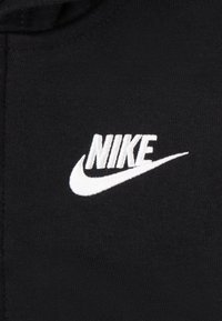 Tessuto di felpa nero con un prominente logo "NIKE" bianco ricamato con design a swoosh. Texture liscia, abbigliamento casual.