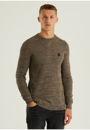 Brauner Strickpullover mit langen Ärmeln und Rundhalsausschnitt, ausgestattet mit einem kleinen Logo auf der Brust und einer strukturierten Oberfläche.