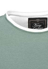 T-shirt a coste verde menta con scollatura rotonda, caratterizzato da un colletto bianco a contrasto e un'etichetta che recita "Key Largo". Texture liscia.