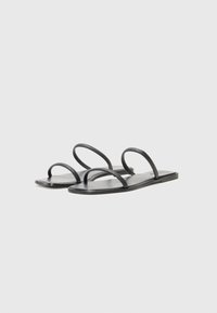 Sorte flate sandaler med tre tynne stropper og en glatt såle. Minimalistisk design med matt finish. Ingen ekstra utsmykninger.