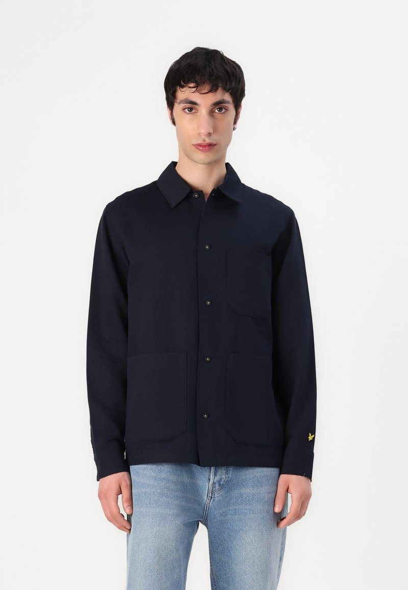 Navyblauwe button-up shirt van katoen met een kraag, twee voorzakken en een klein geborduurd logo op de linker mouw. Gladde textuur.