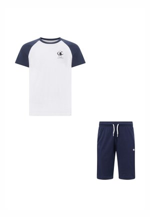 Wit T-shirt met marineblauwe raglanmouwen en logo op de borst, gecombineerd met marineblauwe shorts met trekkoord en klein logo op het linkerbuitenbeen.