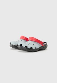 Zoccoli grigi con una fascia rossa e suola nera. Realizzati in materiale leggero, presentano fori di ventilazione e una superficie testurizzata per una migliore aderenza.