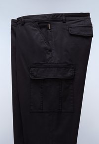 Μαύροι cargo παντελόνια με πλαϊνή τσέπη με καπάκι, μπροστινή πλάγια τσέπη, θηλιές για ζώνη και εμφανή ραφικά στοιχεία.