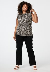 Zwart en crème gestippeld mouwloos topje met een geplooide taille, gecombineerd met zwarte broek en crème instap sandalen met blokhak.
