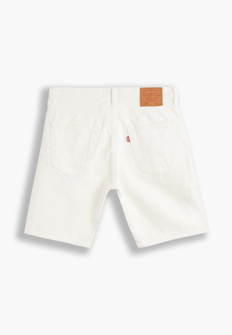 Weiße Denim-Shorts von hinten betrachtet, mit zwei Taschen, Gürtelschlaufen, einem Leder-Logo-Patch und einem kleinen roten Etikett an der rechten Tasche.