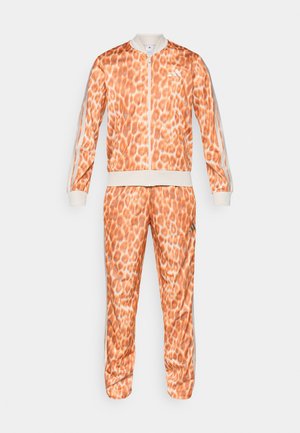 Oranger Trainingsanzug mit Leopardenmuster, bestehend aus einer Reißverschlussjacke und passenden Hosen. Strukturierter, leichter Stoff; drei Streifen Akzente.