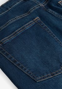 Denim jeans met een donkerblauwe tint, voorzien van een grote achterzak met contrasterende stiksels en een gladde textuur.