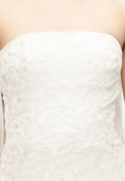 Rihmadeta valge pitsist kleidikeha lillemustriga, mis istub tihedalt inimese ülakehale.