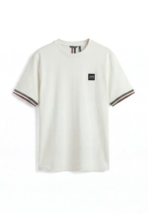 Off-white majica kratkih rukava s okruglim izrezom, prugastim smeđim i sivim manžetama te malom crnom logotipom na lijevoj strani prsnog dijela.
