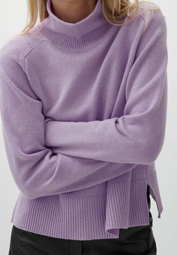 Lila kaulusneule, jossa on röpelöinen tekstuuri, sivuleikkaukset ja pitkät hihat. Neuleessa on rento istuvuus ja pehmeä materiaali.