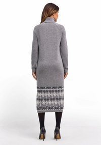 Grijze gebreide jurk met een hoge kraag, lange mouwen en een patroon op de rok met donkere en lichte grijstinten. Glad textuur, nauwsluitend ontwerp.