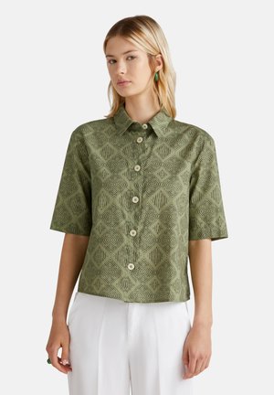Short-sleeve green shirt made of textured fabric featuring a diamond pattern, with a collared neckline and button front closure.