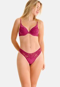 Magenta beha met een gladde cup en bloemenkant details, gecombineerd met een bijpassende slip met kant. Zachte textuur met verstelbare banden.