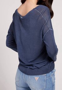 Marineblauer Pullover mit tiefem Rückenausschnitt, geripptem Saum und langen Ärmeln. Hergestellt aus leichtem Strickmaterial mit sichtbaren Nähten.