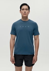 Muška atletska majica kratkih rukava u tamnoplavoj boji, izrađena od lagane, glatke tkanine s suptilnim dizajnom logotipa preko prsa.