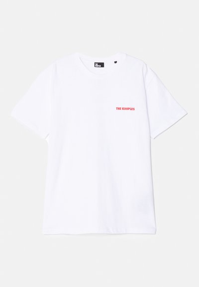 Camiseta blanca de algodón con cuello redondo, mangas cortas y logo rojo "THE KOOPLES" impreso en el lado izquierdo del pecho. Textura suave, ajuste estándar.