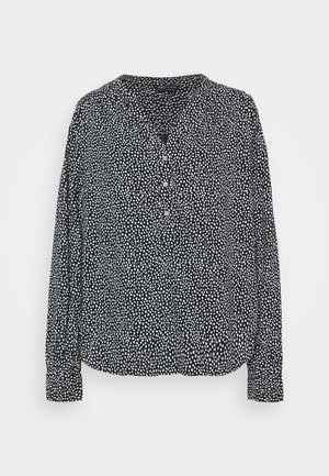 Blusa negra de manga larga con patrón de puntos blancos, cierre con botones en el frente y cuello en V, presentada sobre un fondo blanco liso.