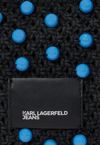 Svart vävt material med blå runda pärlor; har en svart läderetikett präglad med "KARL LAGERFELD JEANS."