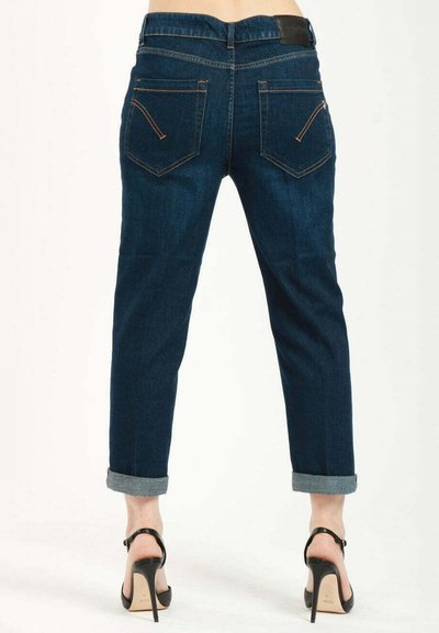 Jeans in denim blu scuro con una vestibilità comoda, orli arrotolati e due tasche posteriori con cuciture a contrasto. Scarpe con tacco alto nere vengono indossate.