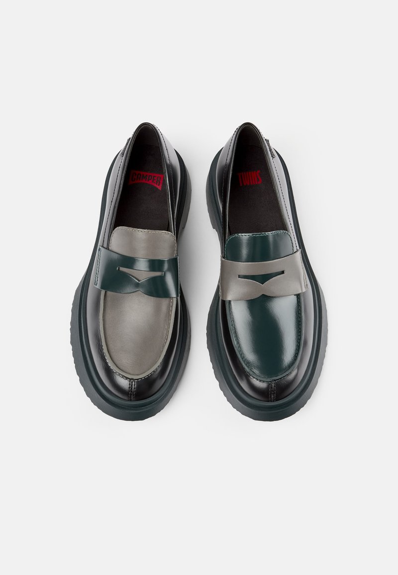 Deux chaussures à enfiler avec un cuir contrasté : l'une est vert foncé et l'autre est grise. Les deux disposent d'une sangle avant texturée et de semelles noires épaisses.