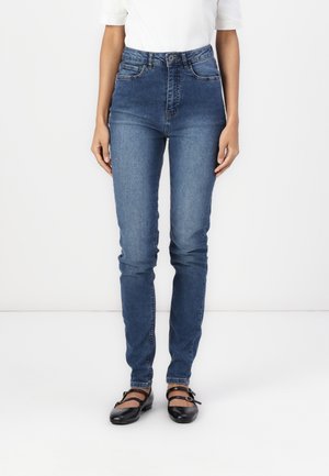 Jeans de mezclilla azul de cintura alta con un corte ajustado, que cuentan con bolsillos frontales, un ligero desvanecimiento y una cremallera con cierre de botón.