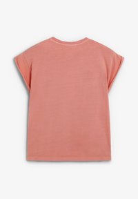 Tricou cu mânecă scurtă în corai deschis, realizat dintr-un material moale. Dispune de un guler rotund și o croială lejeră, cu accente la mânecile rulote.